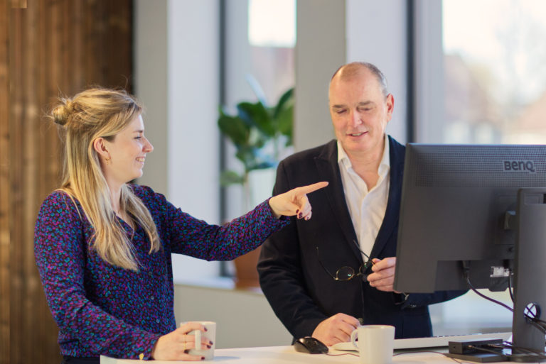 Er staan twee medewerkers van Nieuw Initiatief op een computerscherm te kijken naar kennisplatform Initiatief-Rijk.